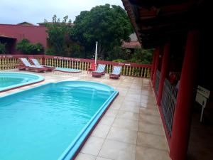 - une piscine avec des chaises et une clôture dans l'établissement Pousada Bromélias - Suítes e Aptos, à Nova Viçosa
