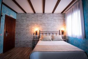een slaapkamer met een groot bed met een bakstenen muur bij Palacito de la Rubia in Chinchón