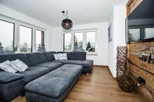 a living room with a gray couch and some windows at Kitz Juwel Top 1 in Hollersbach im Pinzgau