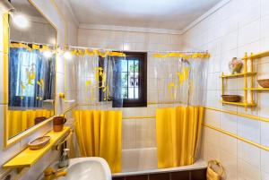 La salle de bains est pourvue de rideaux de douche jaunes et d'un lavabo. dans l'établissement Villa Cortijo del Peñón, à Frigiliana