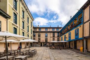 pusty dziedziniec ze stołami, krzesłami i parasolami w obiekcie Apartamento Supercentrico w mieście Oviedo