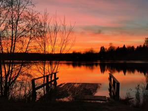 una puesta de sol sobre un cuerpo de agua con un banco en Fishing Club Litvinovo, en Litvinovo