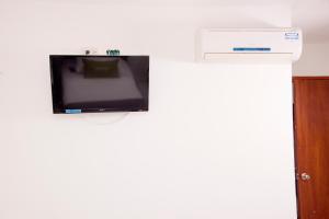TV de pantalla plana colgada en la pared en Ayenda Hotel Coral, en Santa Marta