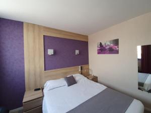 a bedroom with a bed and a purple wall at Contact Hôtel du Relais Thouars in Thouars