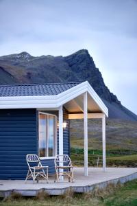 dwa krzesła na ganku niebieskiego domu w obiekcie Nátthagi Luxury Cottage w mieście Snæfellsbær