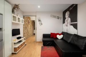 a living room with a black leather couch and a television at Apartamento Supercentrico in Oviedo