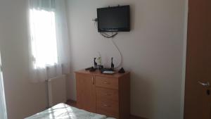 シオーフォクにあるPamela apartman Siófokのベッドルーム1室(ドレッサー、壁掛けテレビ付)