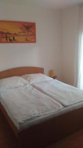 シオーフォクにあるPamela apartman Siófokの白いシーツと壁画が施されたベッド