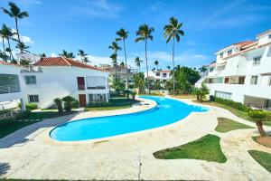 a swimming pool in front of a building with palm trees at Los Corales Beach Village in Punta Cana