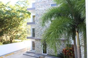 a building with palm trees in front of it at Apartamento Amueblado Amplio Tranquilo Privado Como tu lo Mereces in Santiago de los Caballeros