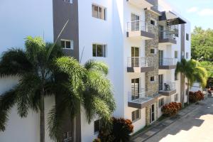聖地亞哥洛斯卡巴的住宿－Apartamento Amueblado Amplio Tranquilo Privado Como tu lo Mereces，一座白色的建筑,前面有棕榈树