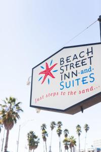 a sign on a building with a palm tree on top of it at Beach Street Inn and Suites in Santa Cruz