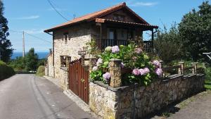 ein kleines Haus mit Blumen an einer Steinmauer in der Unterkunft La Casina de Abo in El Manto