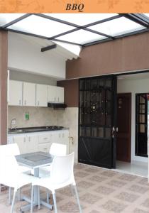 a kitchen with a table and white chairs and a black door at Sueños Vividos Hospedaje in Sogamoso