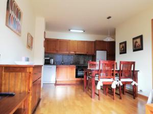 a kitchen with wooden cabinets and a table and chairs at Apartament CA DE GALLISCA B in Pla de l'Ermita