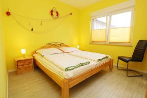 a bedroom with a bed and a chair and a window at Ferienwohnung Wiesenglueck_EHRL in Ostseebad Karlshagen