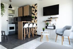 a kitchen with bar stools and a tv on a wall at Sunny Studio Disneyland Paris in Montévrain