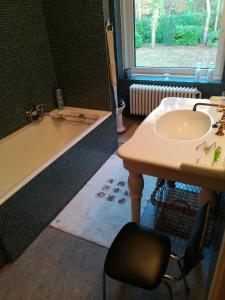 een badkamer met een bad, een wastafel en een tafel bij B+B GOLF SCHILDE in Schilde