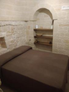a bed in a room with a stone wall at RITORNO AD ITACA in Locorotondo