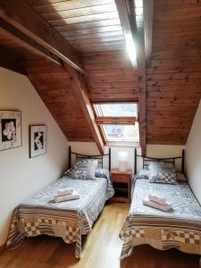 2 łóżka w sypialni na poddaszu z drewnianymi sufitami w obiekcie Apartament Ca de Gallisca w mieście Pla de l'Ermita