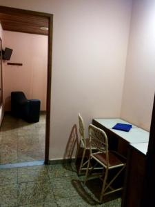 Zimmer mit 2 Stühlen, einem Schreibtisch und einer Tür in der Unterkunft New Star in Rio de Janeiro