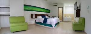 a bedroom with a bed and two green chairs at Hotel Plataneras Confort in Turbo