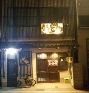 Una bicicleta estacionada frente a un edificio por la noche en Home Sharing Guest House Don en Takayama