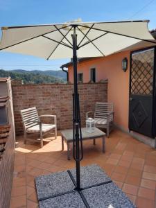 einen Regenschirm auf einer Terrasse mit einem Tisch und Stühlen in der Unterkunft Agriturismo Borgo La Casetta in San Baronto