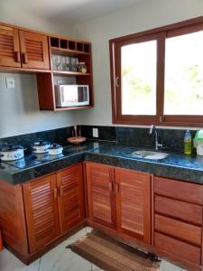 eine Küche mit Holzschränken, einem Waschbecken und einem Fenster in der Unterkunft Flat Pipa Brisas do Amor in Pipa