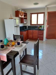 eine Küche mit einem Tisch und Stühlen sowie einem Kühlschrank in der Unterkunft Flat Pipa Brisas do Amor in Pipa