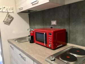 a red microwave sitting on top of a kitchen counter at HappyHome Monolocale Rivarolo Canavese in Rivarolo Canavese