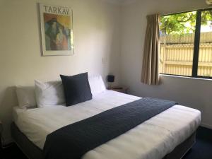 ein Schlafzimmer mit einem großen Bett mit weißer Bettwäsche und einem Fenster in der Unterkunft Claremonte Motor Lodge in Hastings