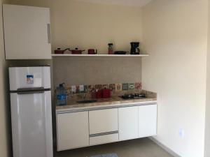 a kitchen with white cabinets and a white refrigerator at Chalés Polinésia in Touros