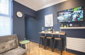 a blue room with a bar with stools and a tv at Yellow Hive Boutique Stay Apt 1 in Belfast
