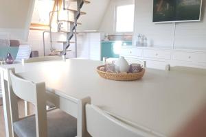 a white kitchen with a white table and chairs at Gezellige chalet in Nieuwpoort - Opkuis al inbegrepen in de prijs in Oostduinkerke