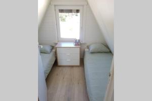een kleine slaapkamer met 2 bedden en een raam bij Gezellige chalet in Nieuwpoort - Opkuis al inbegrepen in de prijs in Oostduinkerke
