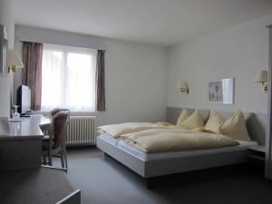 ein weißes Schlafzimmer mit einem Bett, einem Schreibtisch und einem Fenster in der Unterkunft Landhotel Hirschen in Trüllikon