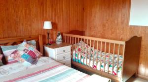 a bedroom with a crib and a wooden wall at Herdade da Hera in Azambuja +55 photos