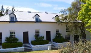 an exterior view of a white house with black doors at Lythgo's Row Colonial Cottages in Pontville