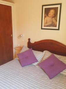 1 cama con almohadas moradas y una foto en la pared en Pa-kuas del Uritorco en Capilla del Monte