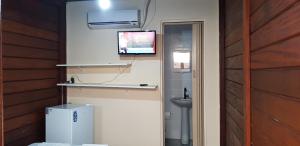 a room with a refrigerator and a tv on the wall at Recanto dos Albatrozes in Boicucanga +53 photos