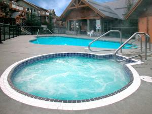 a large swimming pool with blue water in front of a house at Glaciers Reach by Allseason Vacation Rentals in Whistler