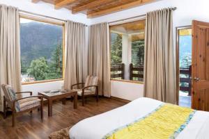 um quarto com uma cama, uma mesa e cadeiras em Hotel Delfryn em Manali