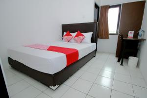 Schlafzimmer mit einem Bett mit roten und weißen Kissen in der Unterkunft Super OYO 1678 Jati Exclusive Homestay in Bengkulu