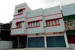 a white building with red windows and doors at Super OYO 1678 Jati Exclusive Homestay in Bengkulu