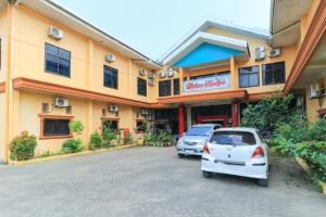Hotel Mutiara Khadijah في Sudiang: سيارتين متوقفتين امام مبنى