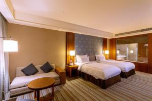 a hotel room with two beds and a couch at Fullon Hotel Tamsui Fishermen's Wharf in Tamsui +75 photos