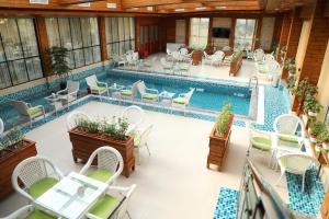 an indoor swimming pool with chairs and tables and a swimming pool at Kabul Star Hotel & Restaurant in Shīrpūr