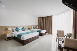 Habitación de hotel con 2 camas, mesa y sillas en Ban Me Central Hotel en Buon Ma Thuot