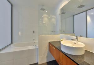y baño con lavabo, bañera y espejo. en Sea Side 110 en Mandurah